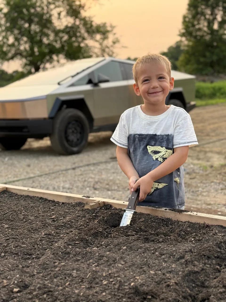 A young boy digging in a raised garden bed
