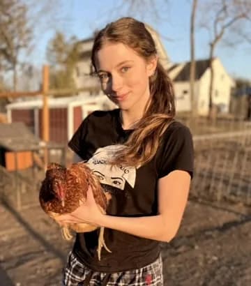 A girl smiling while cuddling a chicken